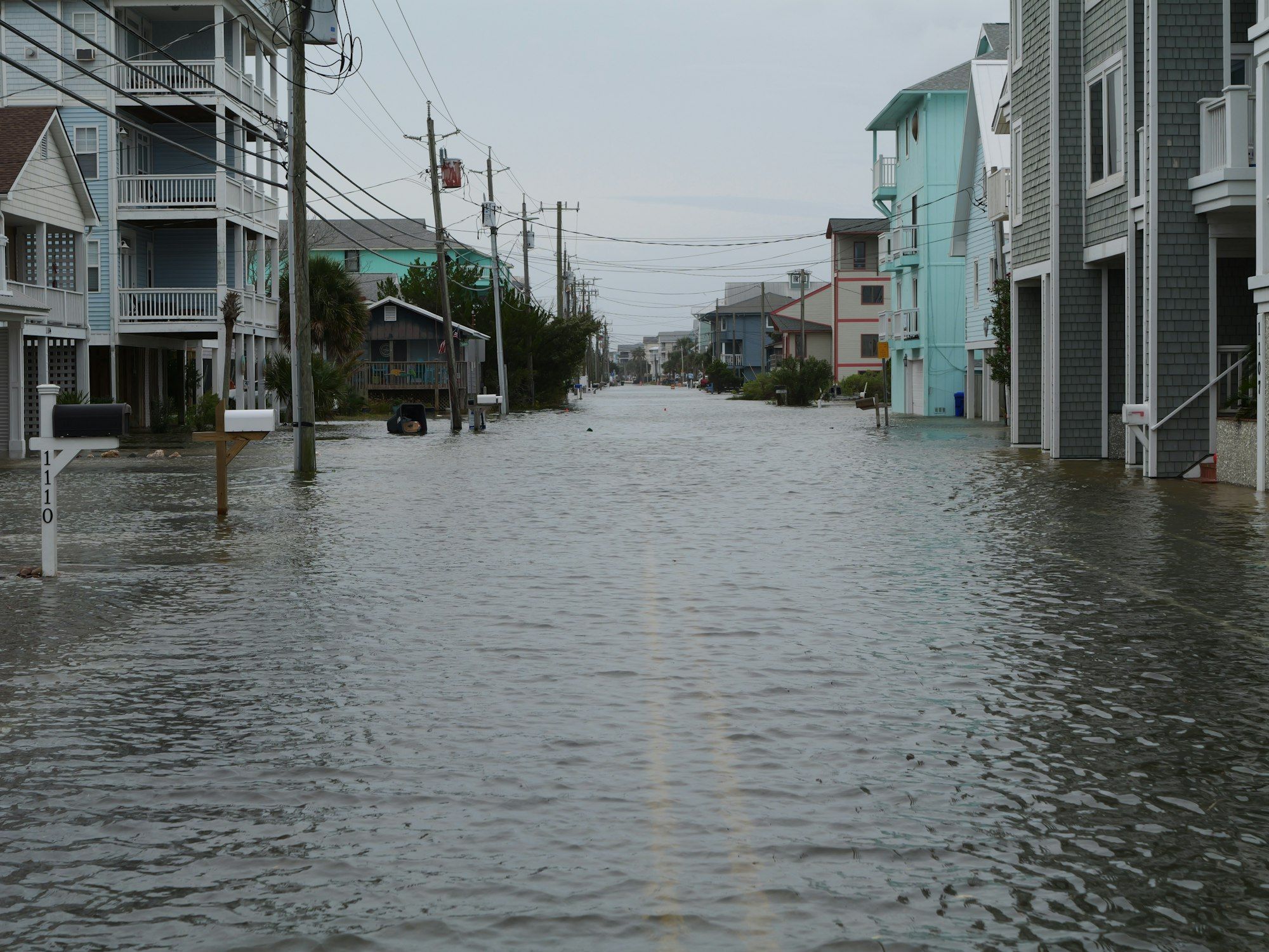 Flooded street lined with raised beach houses in Carolina Beach, NC